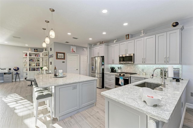 kitchen featuring stainless steel appliances, tasteful backsplash, a breakfast bar area, and a sink