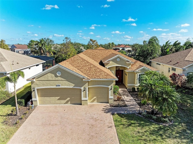 view of front of house featuring decorative driveway, an attached garage, stucco siding, and roof with shingles