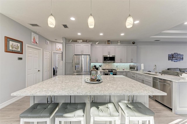 kitchen with decorative backsplash, a sink, gray cabinets, and appliances with stainless steel finishes