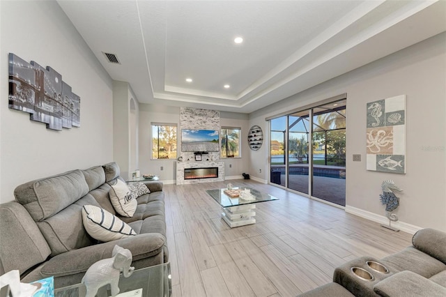 living room with wood finished floors, a tray ceiling, a healthy amount of sunlight, and visible vents
