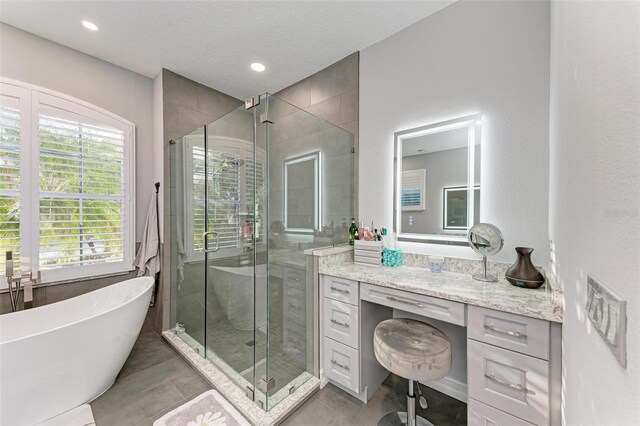 bathroom featuring a textured ceiling, tile patterned flooring, a soaking tub, and a shower stall