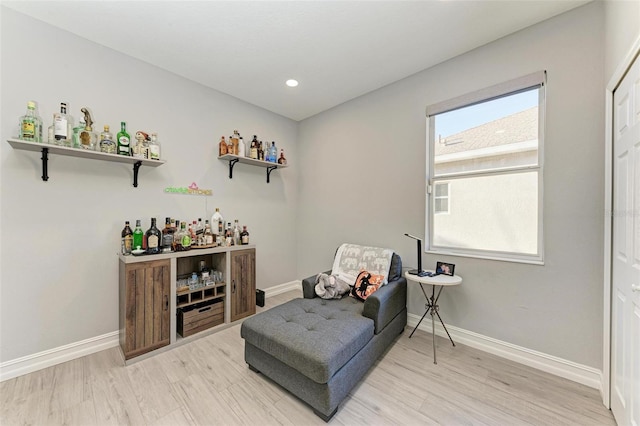 living area featuring a bar, recessed lighting, baseboards, and light wood-style floors