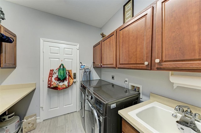 laundry area with washing machine and dryer, light wood-style floors, cabinet space, and a sink