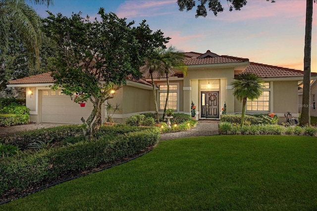 mediterranean / spanish house featuring a yard and a garage