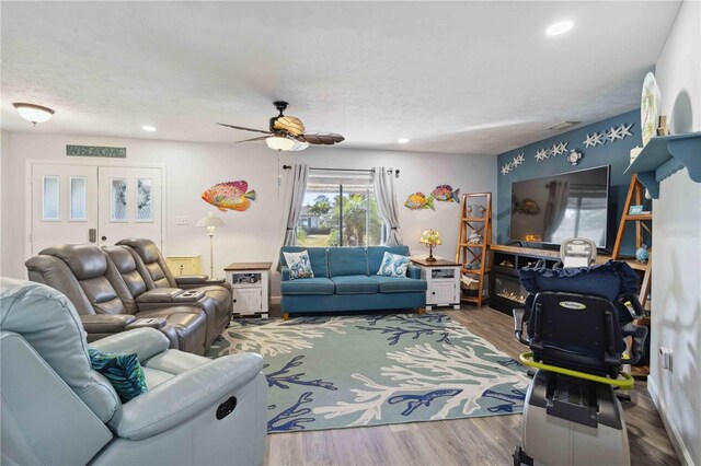 living room with hardwood / wood-style floors, a textured ceiling, and ceiling fan