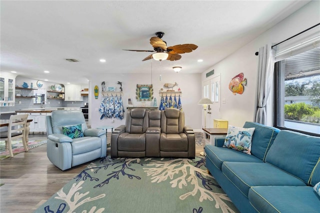 living room featuring ceiling fan, light wood-type flooring, and sink