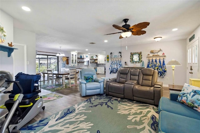 living room featuring hardwood / wood-style flooring, ceiling fan with notable chandelier, and a textured ceiling