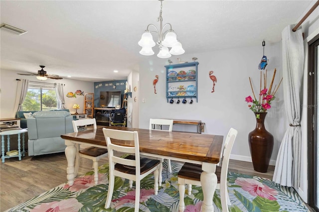 dining room featuring ceiling fan with notable chandelier and hardwood / wood-style flooring