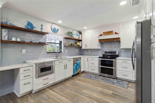 kitchen featuring sink, light hardwood / wood-style flooring, decorative backsplash, white cabinetry, and stainless steel appliances