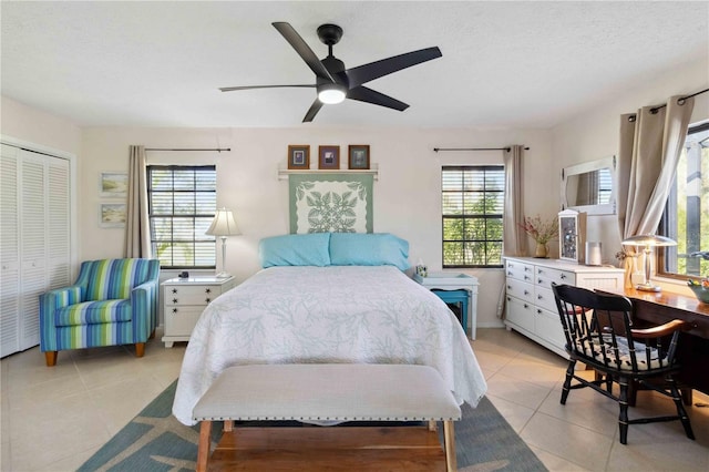 tiled bedroom featuring ceiling fan, a textured ceiling, and a closet