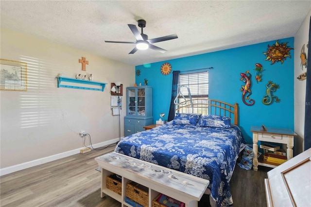 bedroom with hardwood / wood-style flooring, ceiling fan, and a textured ceiling