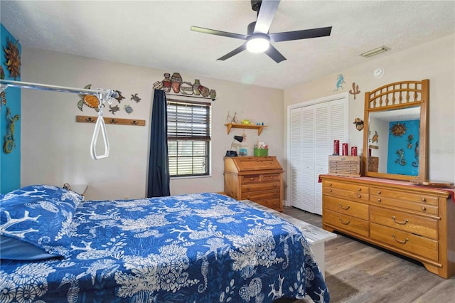 bedroom featuring hardwood / wood-style floors, ceiling fan, a textured ceiling, and a closet