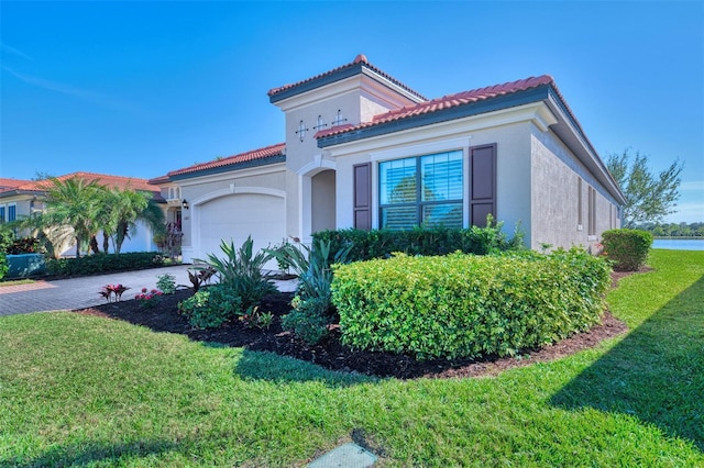 mediterranean / spanish house with a garage and a front lawn