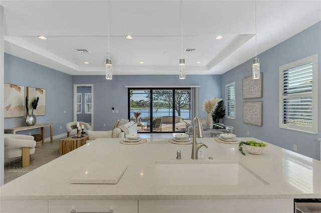 kitchen featuring sink, light stone countertops, and hanging light fixtures