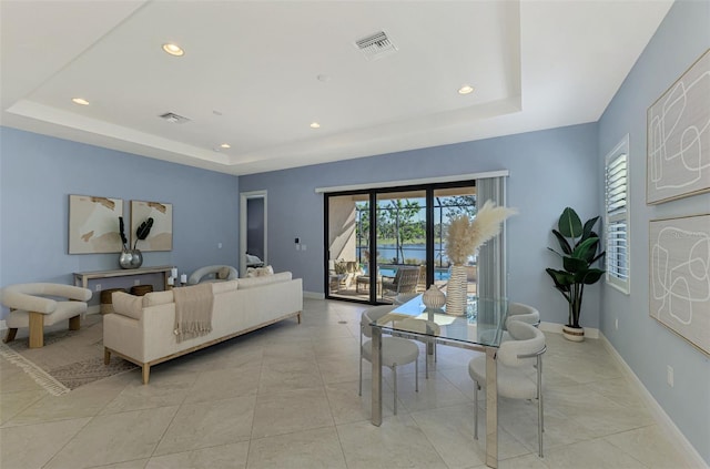 living room featuring a raised ceiling and light tile patterned floors