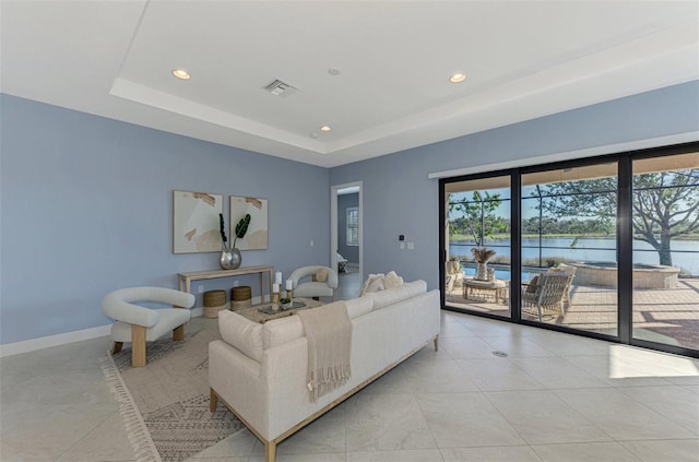 living room with a water view and a tray ceiling