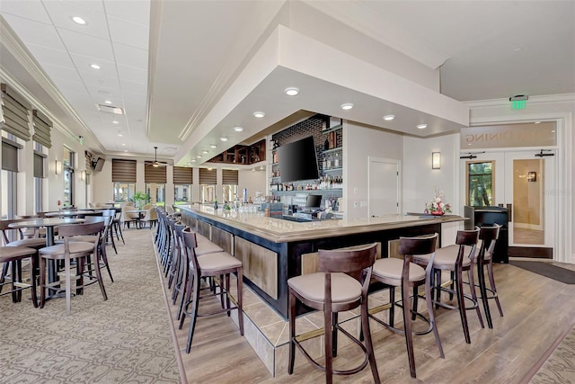 bar with light hardwood / wood-style floors and crown molding