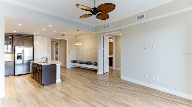 kitchen featuring sink, stainless steel fridge with ice dispenser, crown molding, an island with sink, and dark brown cabinets