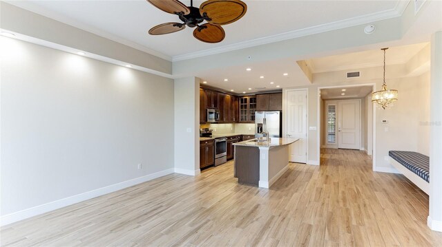 kitchen with pendant lighting, an island with sink, appliances with stainless steel finishes, dark brown cabinets, and light hardwood / wood-style floors