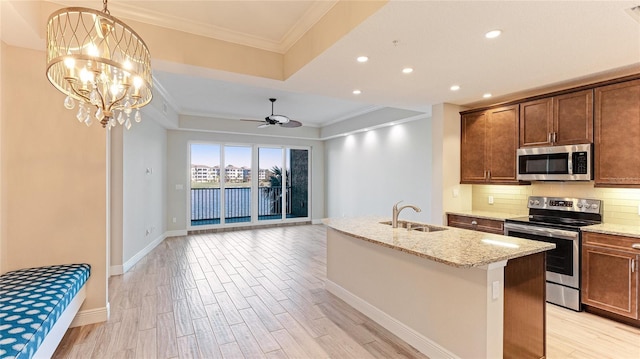 kitchen featuring ceiling fan with notable chandelier, stainless steel appliances, a kitchen island with sink, sink, and light hardwood / wood-style floors