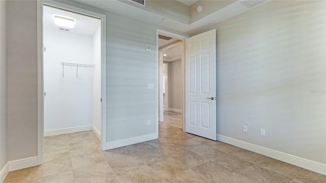 unfurnished bedroom featuring a walk in closet, a closet, and light tile patterned floors