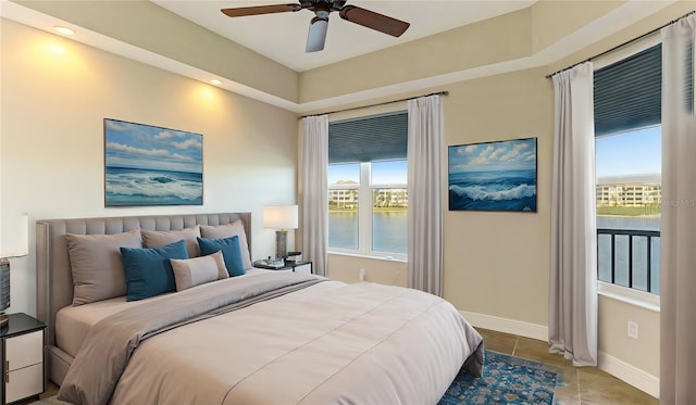 bedroom with a water view, baseboards, tile patterned flooring, and ceiling fan