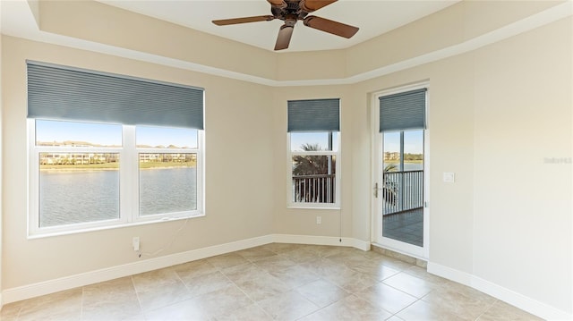 spare room featuring a ceiling fan, a water view, baseboards, and light tile patterned flooring