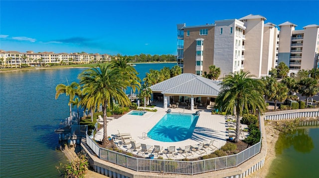 community pool featuring fence, a water view, and a patio area
