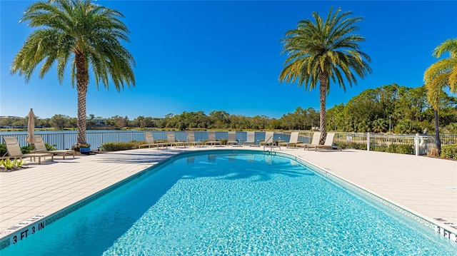 community pool with fence, a patio area, and a water view