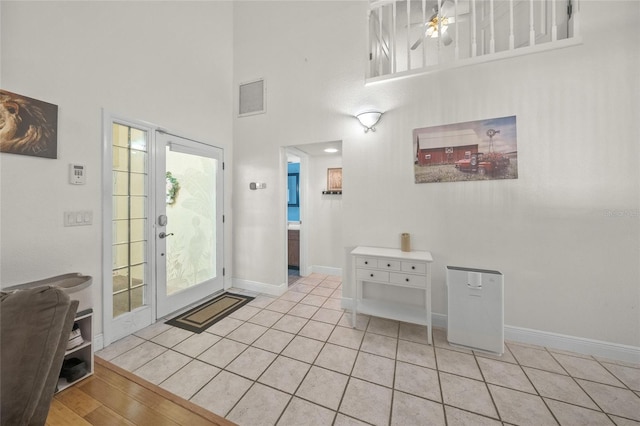 foyer entrance featuring ceiling fan, a wealth of natural light, a high ceiling, and light hardwood / wood-style flooring