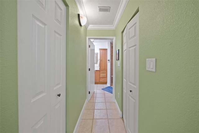 hall featuring crown molding, light tile patterned floors, and a textured ceiling