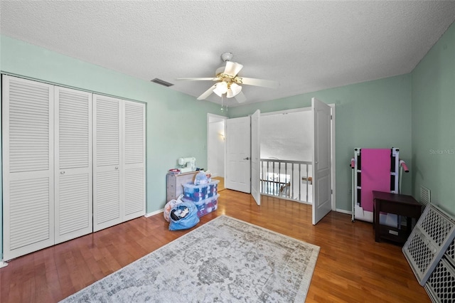 bedroom with hardwood / wood-style flooring, ceiling fan, a textured ceiling, and a closet