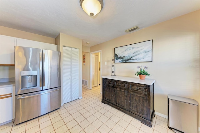 kitchen with dark brown cabinetry, white cabinetry, stainless steel fridge with ice dispenser, a textured ceiling, and light tile patterned flooring