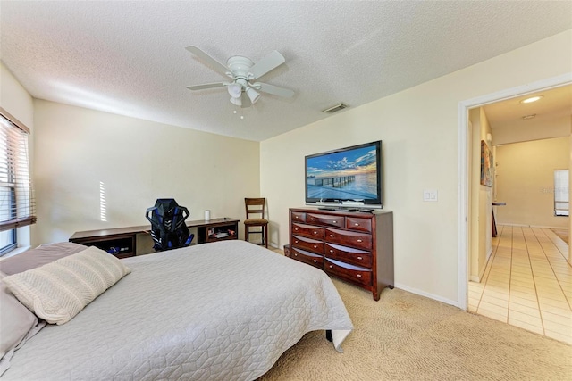 bedroom featuring ceiling fan, light colored carpet, and a textured ceiling