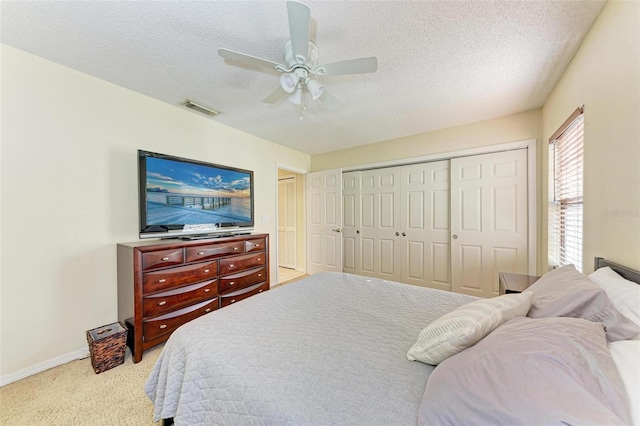 bedroom with a textured ceiling, light colored carpet, and ceiling fan