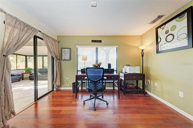 office featuring wood-type flooring, a textured ceiling, and a wealth of natural light