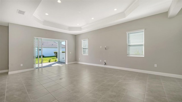 tiled empty room featuring a tray ceiling