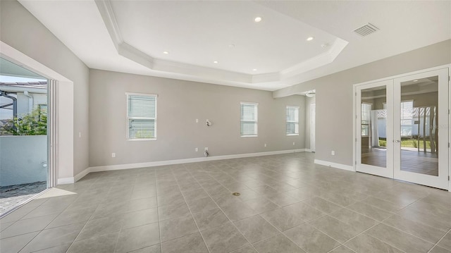 spare room with a raised ceiling, crown molding, and french doors