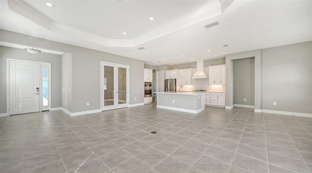 unfurnished living room featuring light tile patterned floors and a tray ceiling