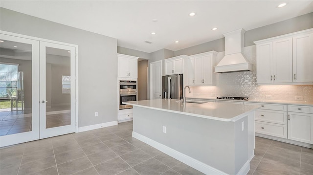 kitchen with premium range hood, white cabinets, sink, appliances with stainless steel finishes, and light tile patterned flooring