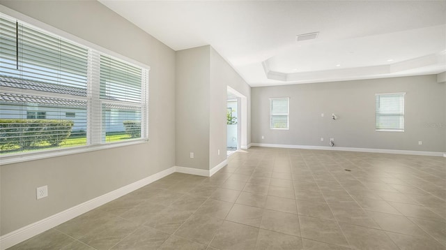 unfurnished room with a tray ceiling and light tile patterned flooring