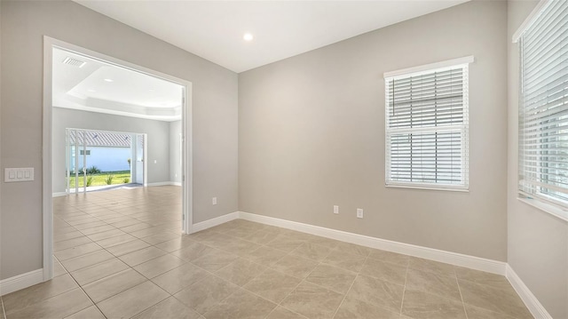 tiled spare room with a tray ceiling and a healthy amount of sunlight