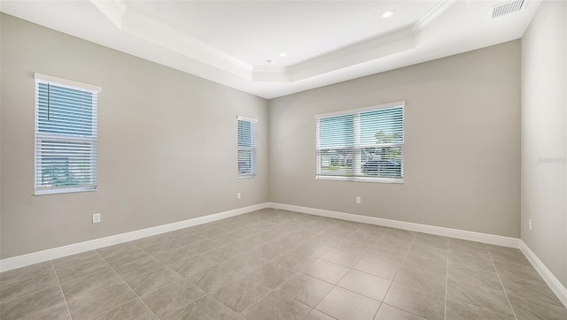 tiled spare room featuring a raised ceiling and crown molding