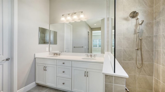 bathroom featuring tile patterned flooring, a tile shower, and vanity