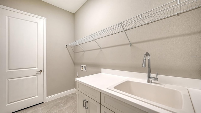 laundry room featuring cabinets, sink, light tile patterned floors, and washer hookup