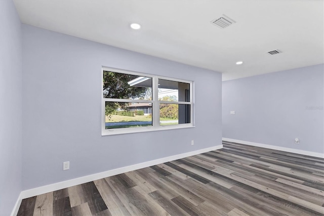 spare room featuring visible vents, baseboards, and wood finished floors