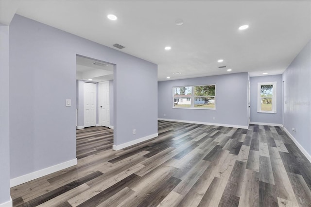 unfurnished living room with dark wood finished floors, visible vents, and baseboards