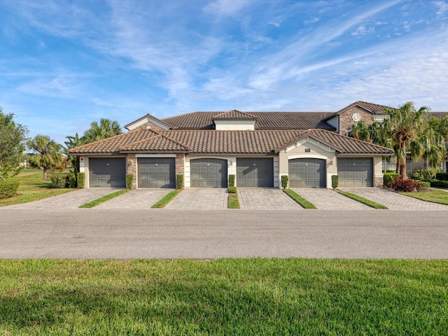 mediterranean / spanish house featuring a garage and a front lawn