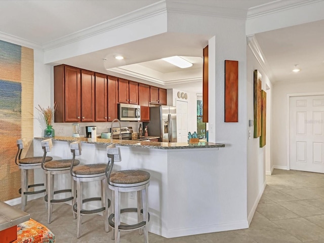 kitchen with light tile patterned floors, ornamental molding, stone countertops, kitchen peninsula, and stainless steel appliances