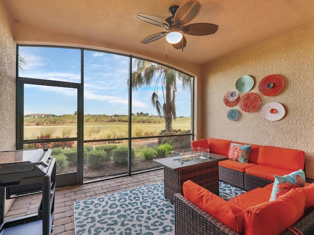 sunroom featuring ceiling fan and a rural view